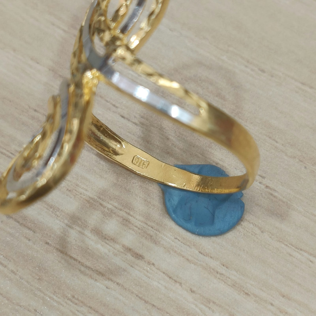 Close-up of the 916 stamp inside the gold band of a two-tone swirl ring