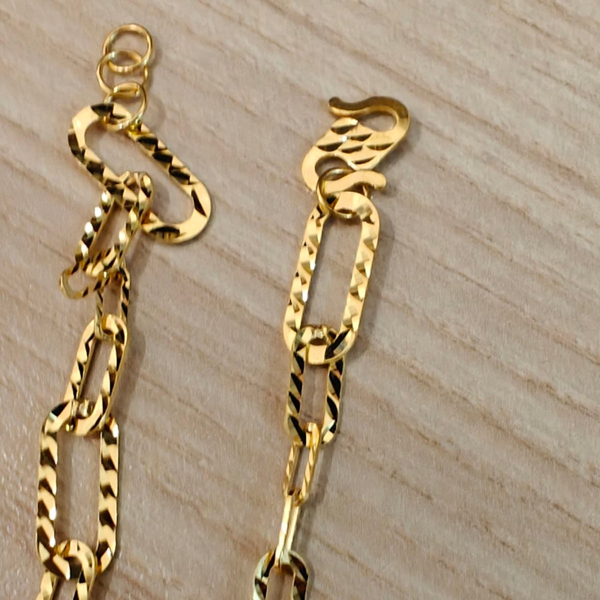 Close-up of the 916 gold fancy link bracelet hook clasp, three adjustment rings and faceted elongated links on wood