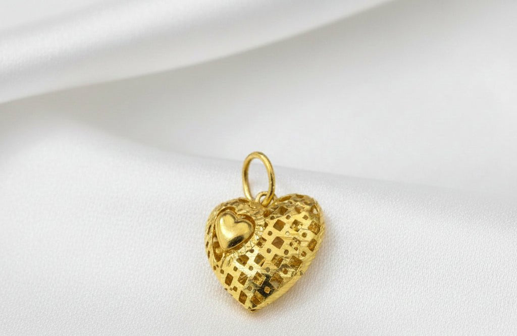 Close angled view of the gold heart pendant, showing the mini-heart accent, reflective square pattern and upright hanging loop