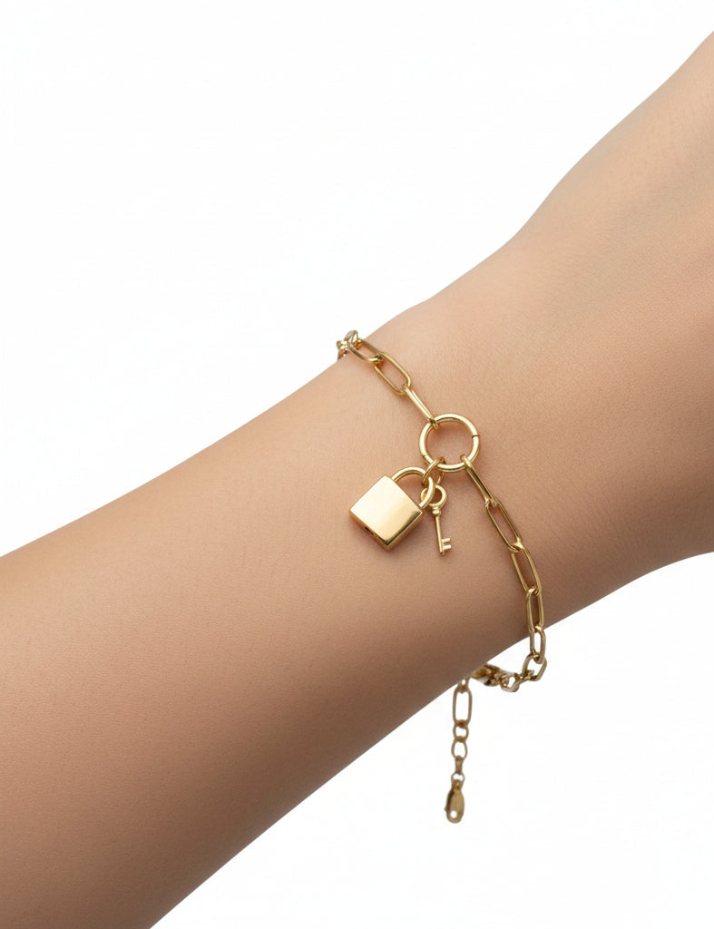 916 gold Lock and Key paperclip bracelet worn on a wrist, showing the polished padlock, key charm, centre ring and dangling clasp