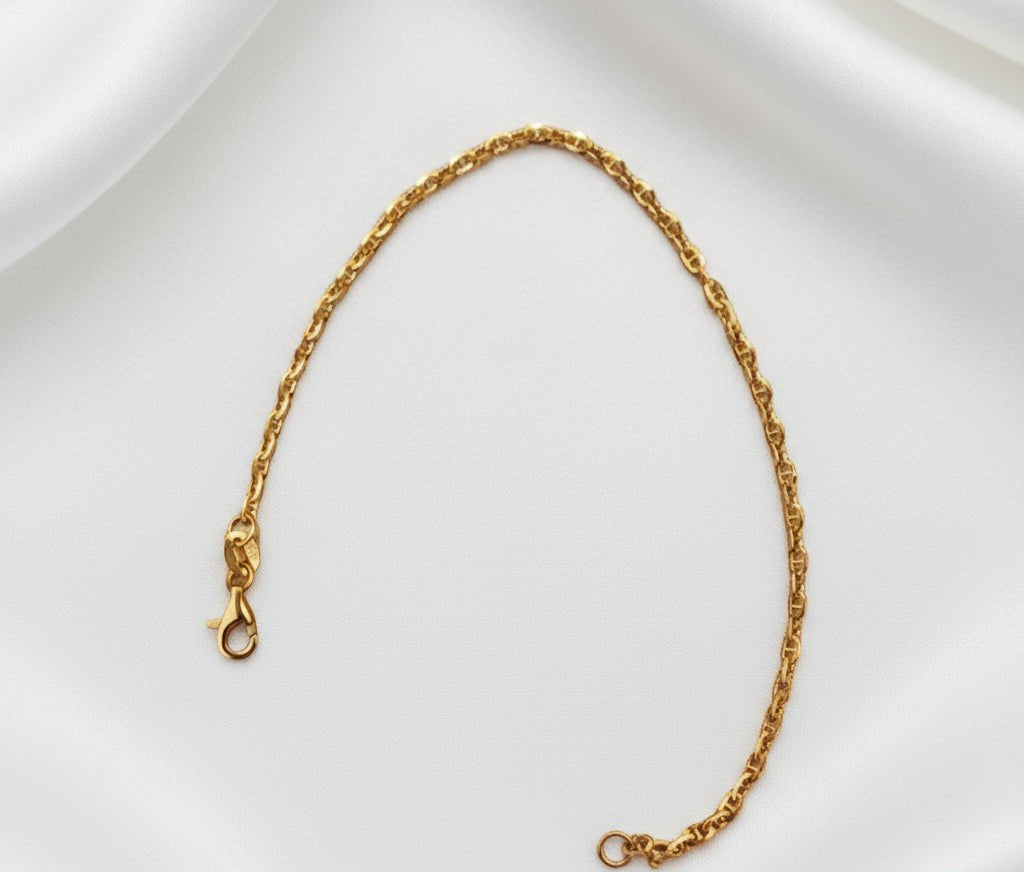 Full twisted-link gold bracelet arranged in an elongated open curve on white fabric, with clasp and end ring visible