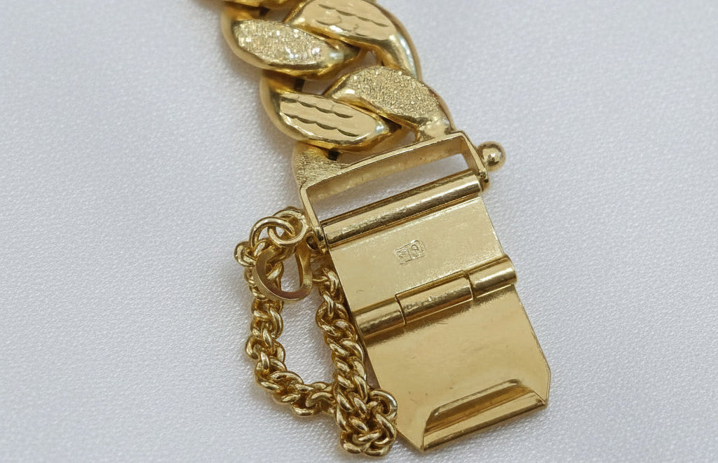 Close-up of the Milo bracelet open box clasp, safety chain and textured gold links