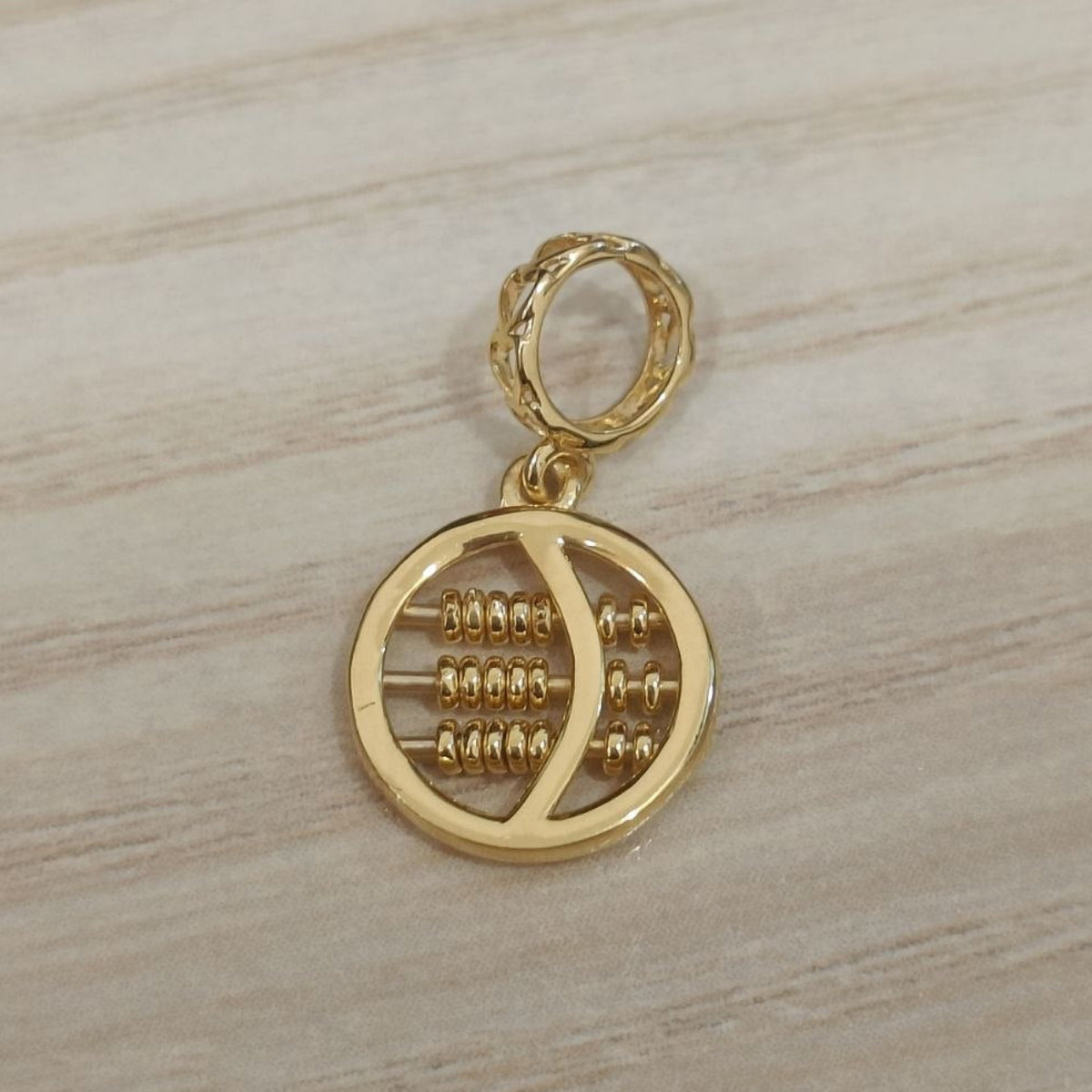 Reverse view of a 916 gold round abacus pendant showing its circular frame, bead rows and patterned bail