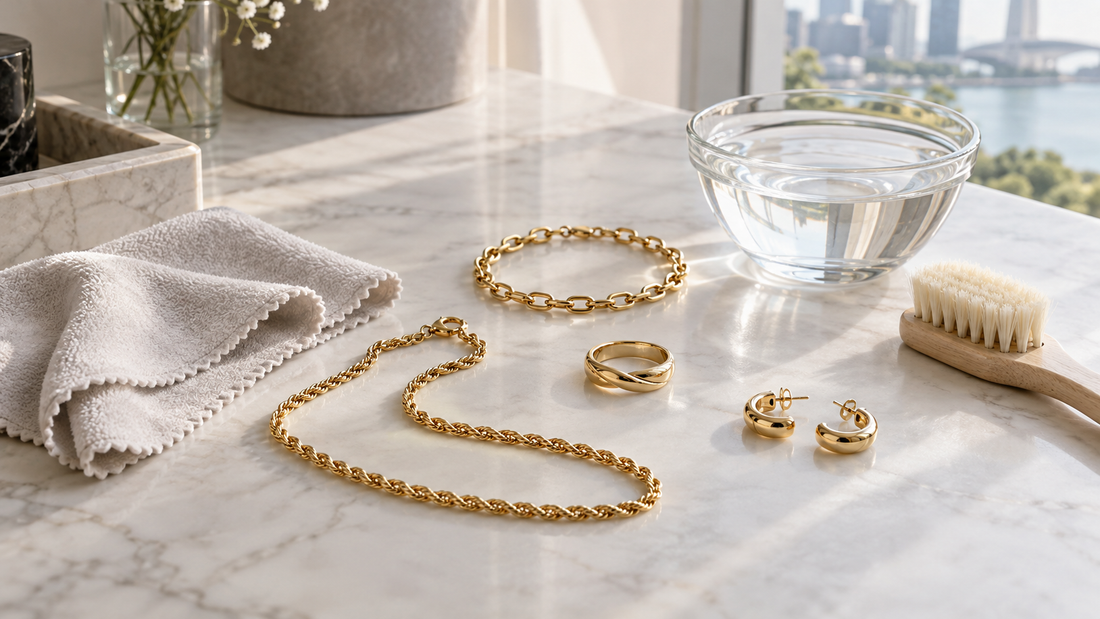 Generic yellow-gold jewellery beside a soft cloth, clean water and a soft brush for gentle at-home care.