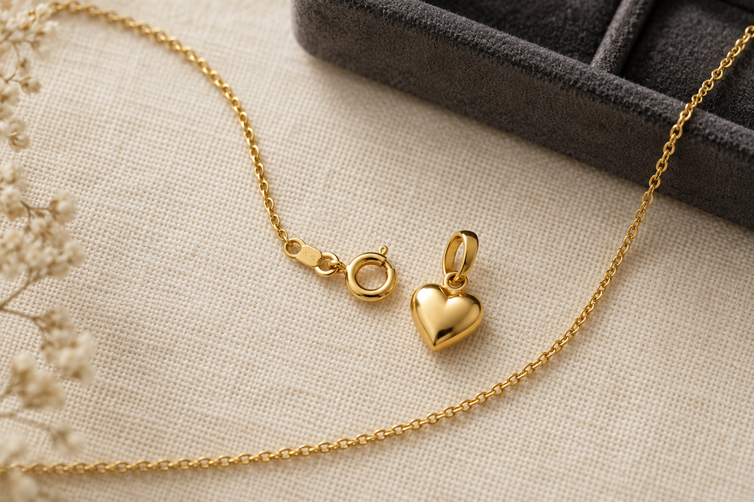 Generic yellow-gold heart pendant, oval bail and fine chain clasp arranged on ivory cloth for a fit comparison.