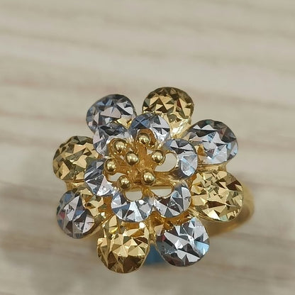 Front view of a 916 gold two-tone floral cluster ring with faceted petals on pale wood