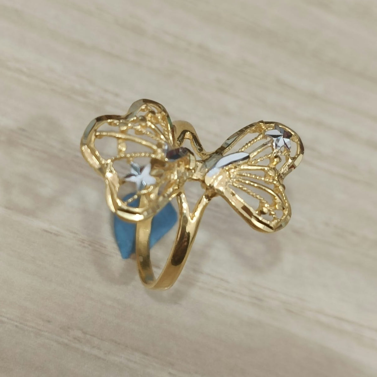 Angled view of a 916 gold two-tone butterfly ring showing openwork wing details and its polished band