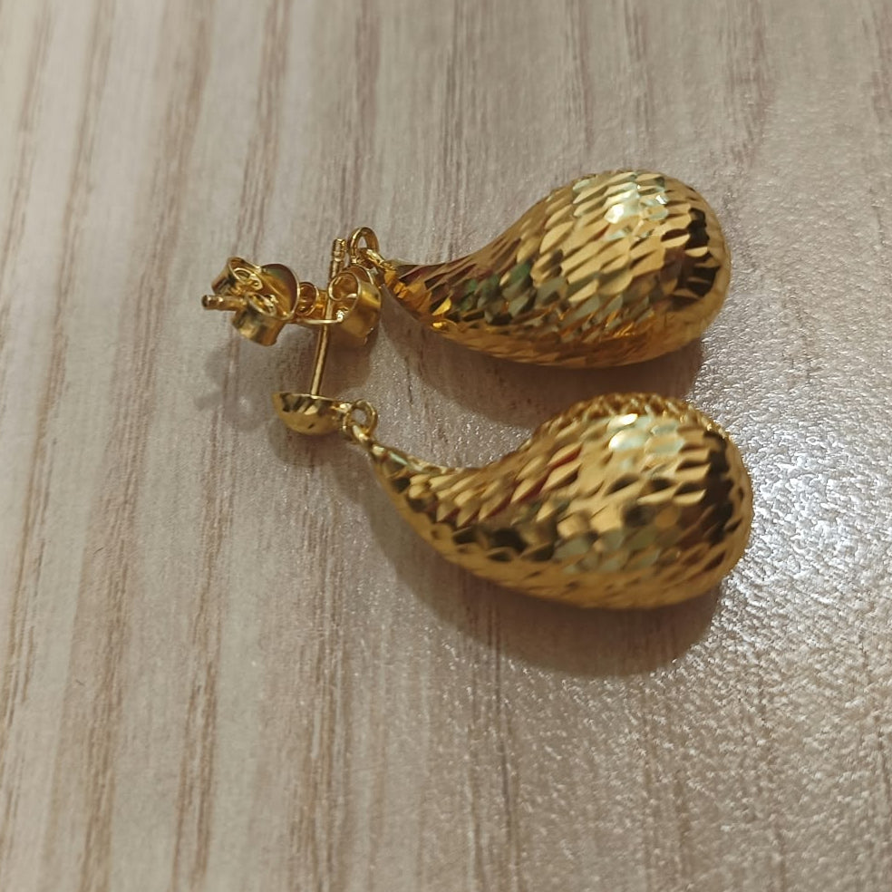 Angled view of 916 gold teardrop earrings showing their faceted gold surfaces, posts and push backs