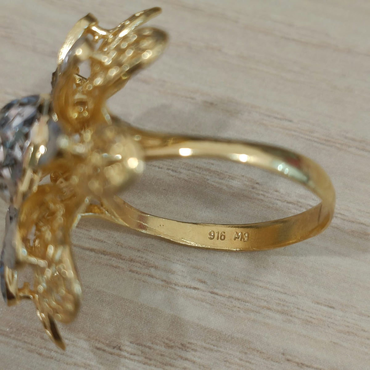 Close-up of the 916 stamp inside the gold band of a two-tone daisy ring