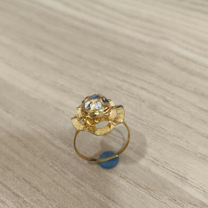 Angled view of a 916 gold two-tone lotus ring showing its layered flower design and gold band on pale wood