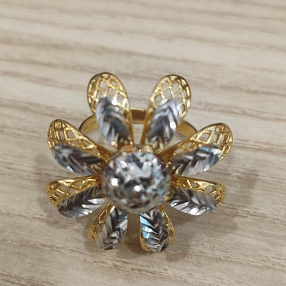 Front view of a 916 gold two-tone daisy ring showing its rounded centre and patterned flower petals on pale wood