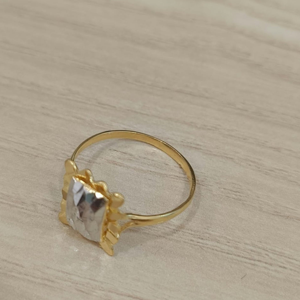 Angled view of a 916 gold two-tone Biscot V3 ring showing its rectangular design and circular gold band
