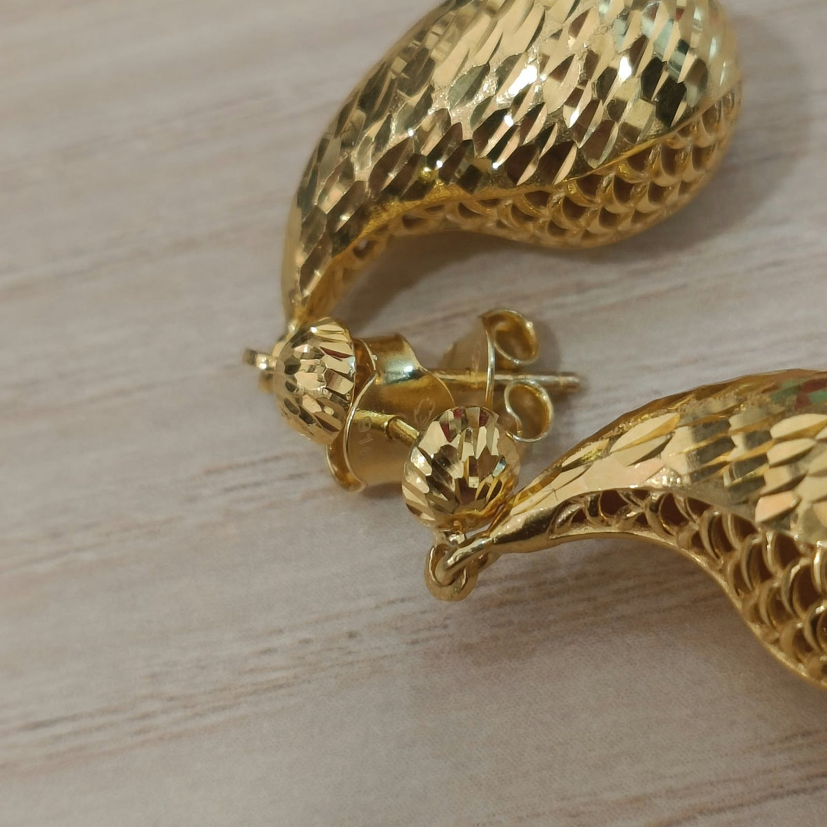 Close-up of 916 gold teardrop earrings showing the textured stud tops, posts, push backs and openwork drop details
