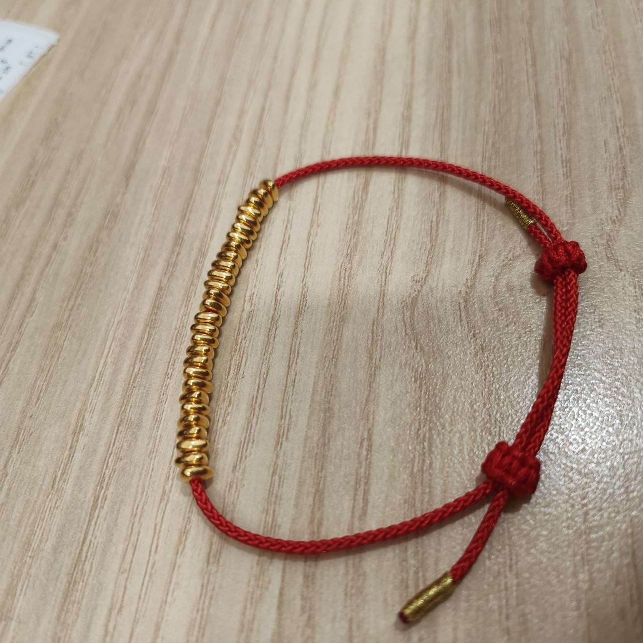 999 gold bead strand bracelet with red adjustable cord - angled view