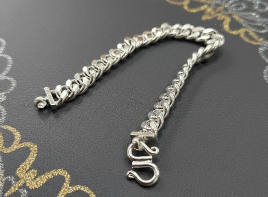 Full angled front view of the silver Cuban bracelet on a dark display surface, showing the complete link chain, end fittings and open S-shaped hook clasp