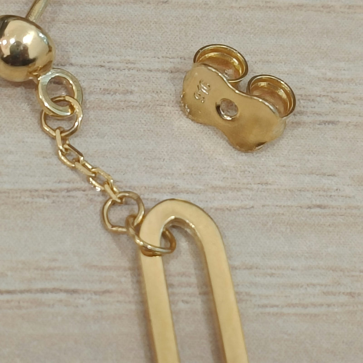 Close-up of 916 gold paperclip dangle earring showing the chain connection, stud and butterfly back