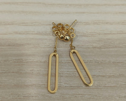 Pair of 916 gold paperclip dangle earrings with elongated open drops, short chains and round stud tops on a wood surface