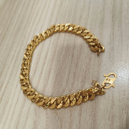 Cowboy-link gold bracelet arranged in a circle on a wood-grain surface