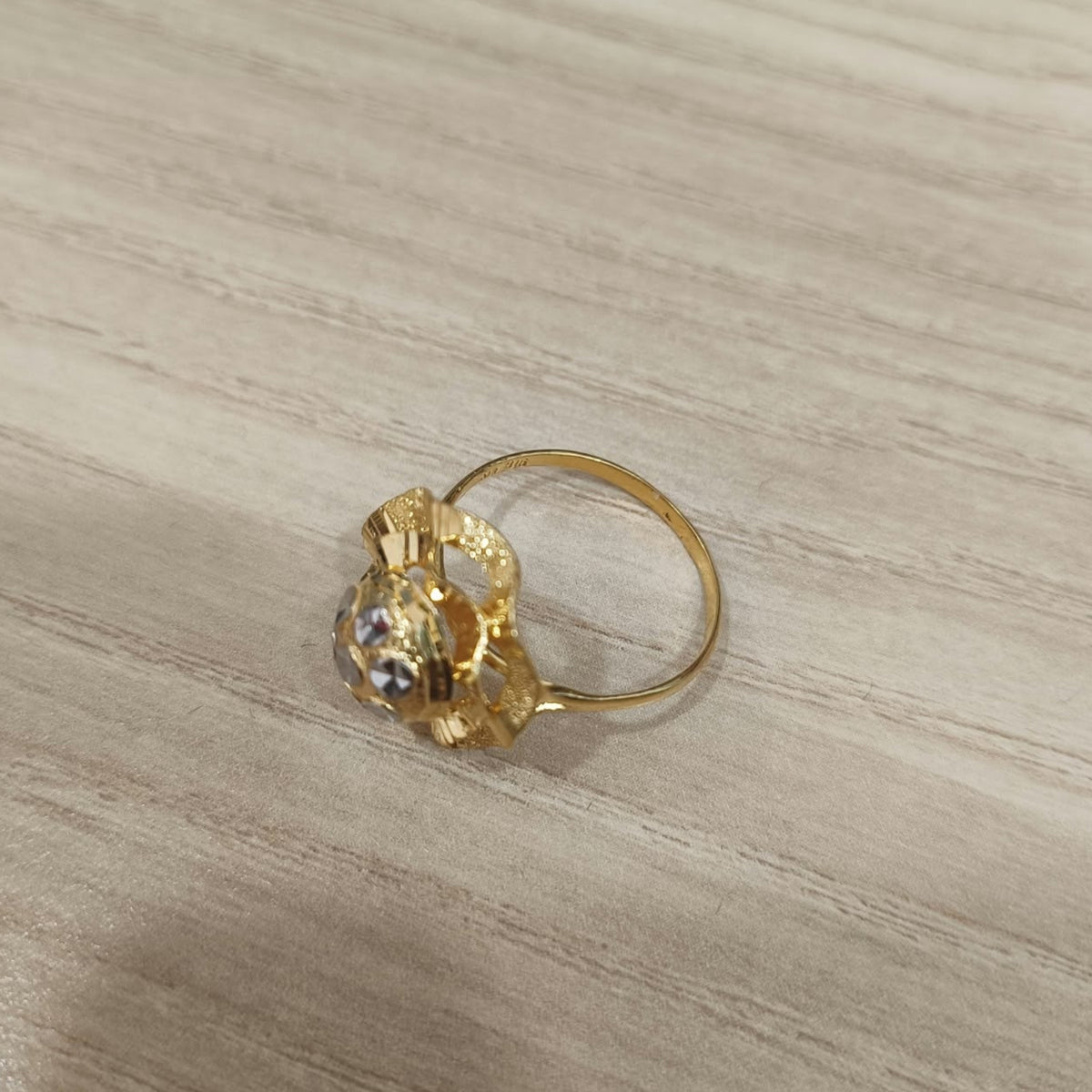 Side view of a 916 gold two-tone lotus ring showing its raised flower profile and circular band