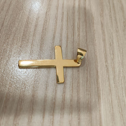 Gold cross pendant viewed from the opposite angle on a wood-grain surface