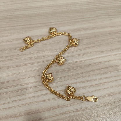 916 gold Wanzi six-heart bracelet arranged in an S curve showing faceted charms and clasp on pale wood