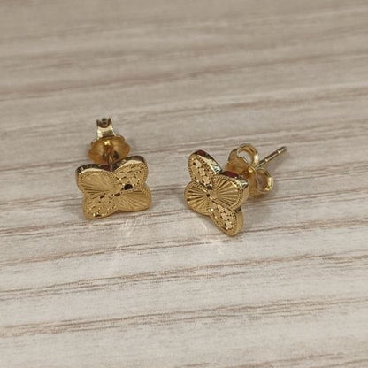 Front view of 916 gold four-petal flower stud earrings with patterned details and butterfly backs
