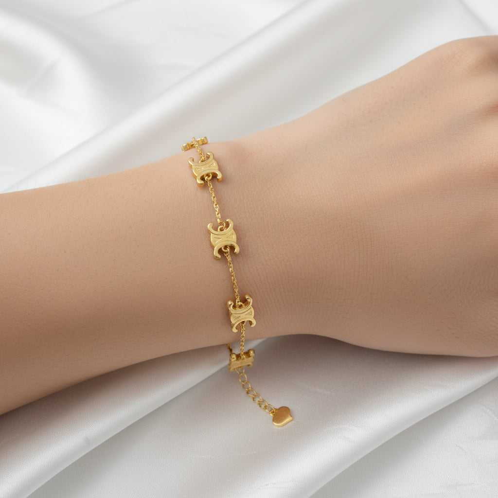 916 gold scroll link bracelet worn on a wrist, showing engraved curled motifs and a dangling heart-shaped extension tag