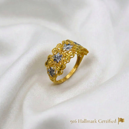 Angled view of the 916 gold Serenity Petal ring with silver-colour flowers and yellow-gold openwork on white fabric