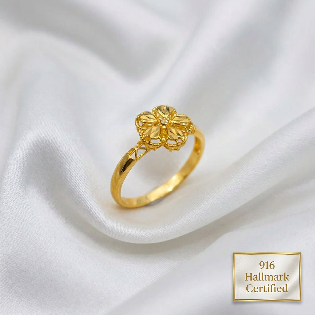 Angled view of a 916 gold blossom ring with faceted petals, beaded edges and openwork shoulders on white fabric