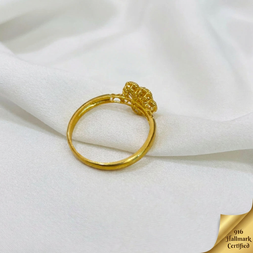Side profile of the 916 gold blossom ring showing the raised flower and openwork shoulders on white fabric
