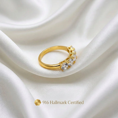 Angled side view of 916 gold eternity-style ring with round silver-coloured accents on white fabric
